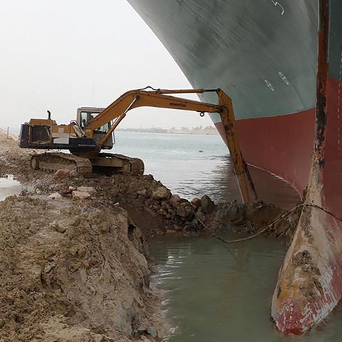 Ein Bagger schaufelt am Frachter "Ever Given", der im Suezkanal auf Grund gelaufen ist und feststeckt