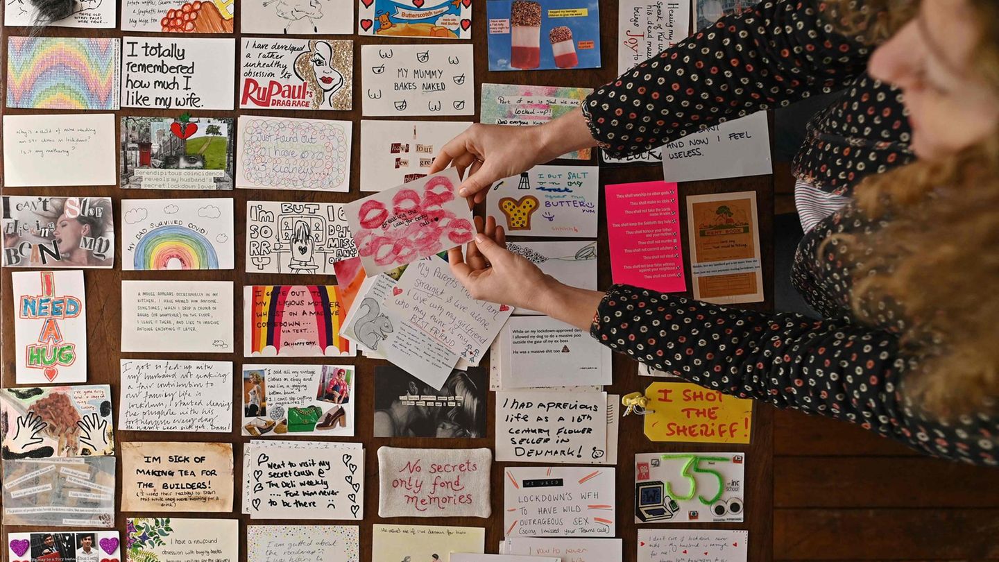 Eleanore Tattersfield sortiert zahlreiche bunt gestaltete Postkarten auf einem Tisch