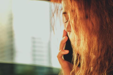 Frau schließt die Augen, während sie telefoniert