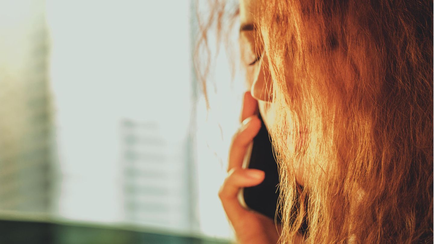 Frau schließt die Augen, während sie telefoniert