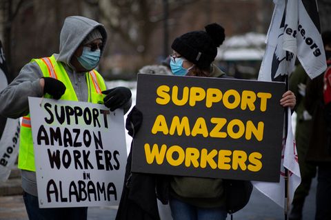 Zwei Personen demonstrieren mit Schildern für die Rechte von Amazon-Mitarbeitenden