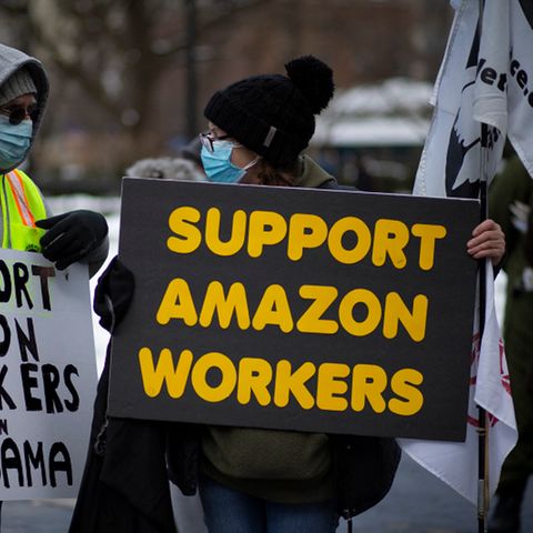 Zwei Personen demonstrieren mit Schildern für die Rechte von Amazon-Mitarbeitenden