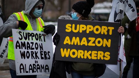 Zwei Personen demonstrieren mit Schildern für die Rechte von Amazon-Mitarbeitenden
