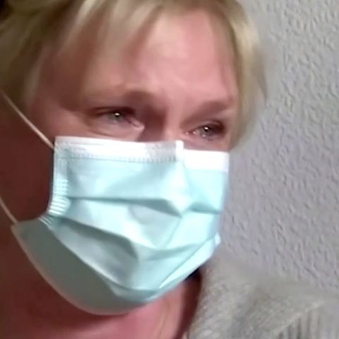 Eine Frau mit kurzen blonden Haaren und OP-Maske hat Freudentränen in den Augen