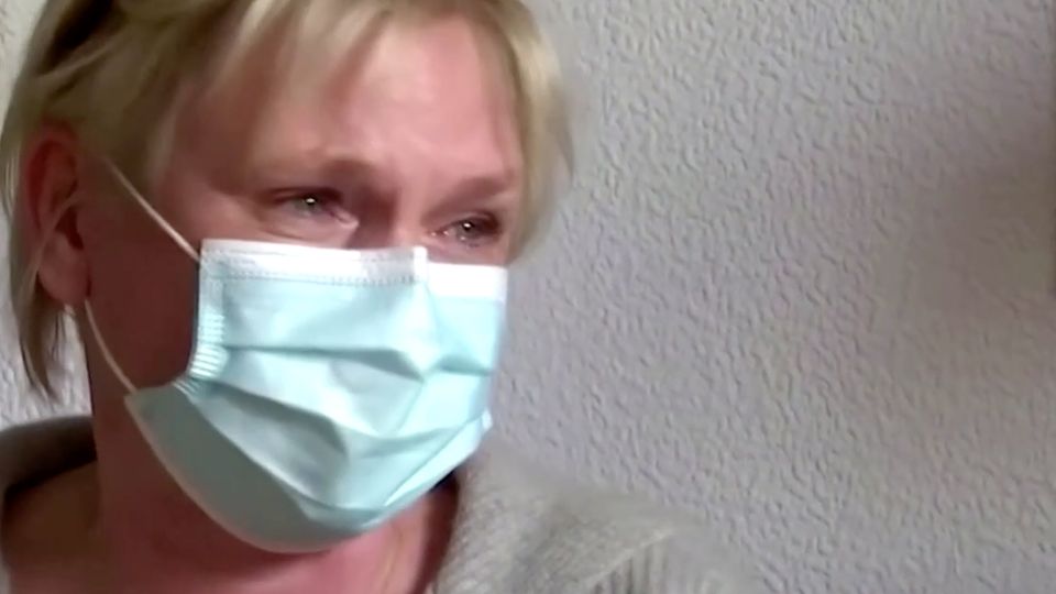 Corona Impfung Freudentränen Frau Eine Frau mit kurzen blonden Haaren und OP-Maske hat Freudentränen in den Augen