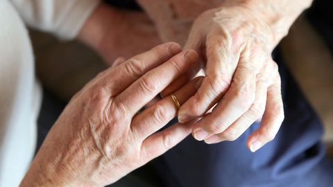 Älterer Mann steckt Ring an Finger von älterer Frau.