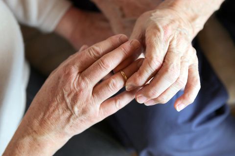 Älterer Mann steckt Ring an Finger von älterer Frau.