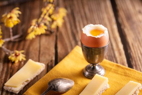 Frühstückstisch mit Käsebroten und einem weich gekochten Ei im Becher