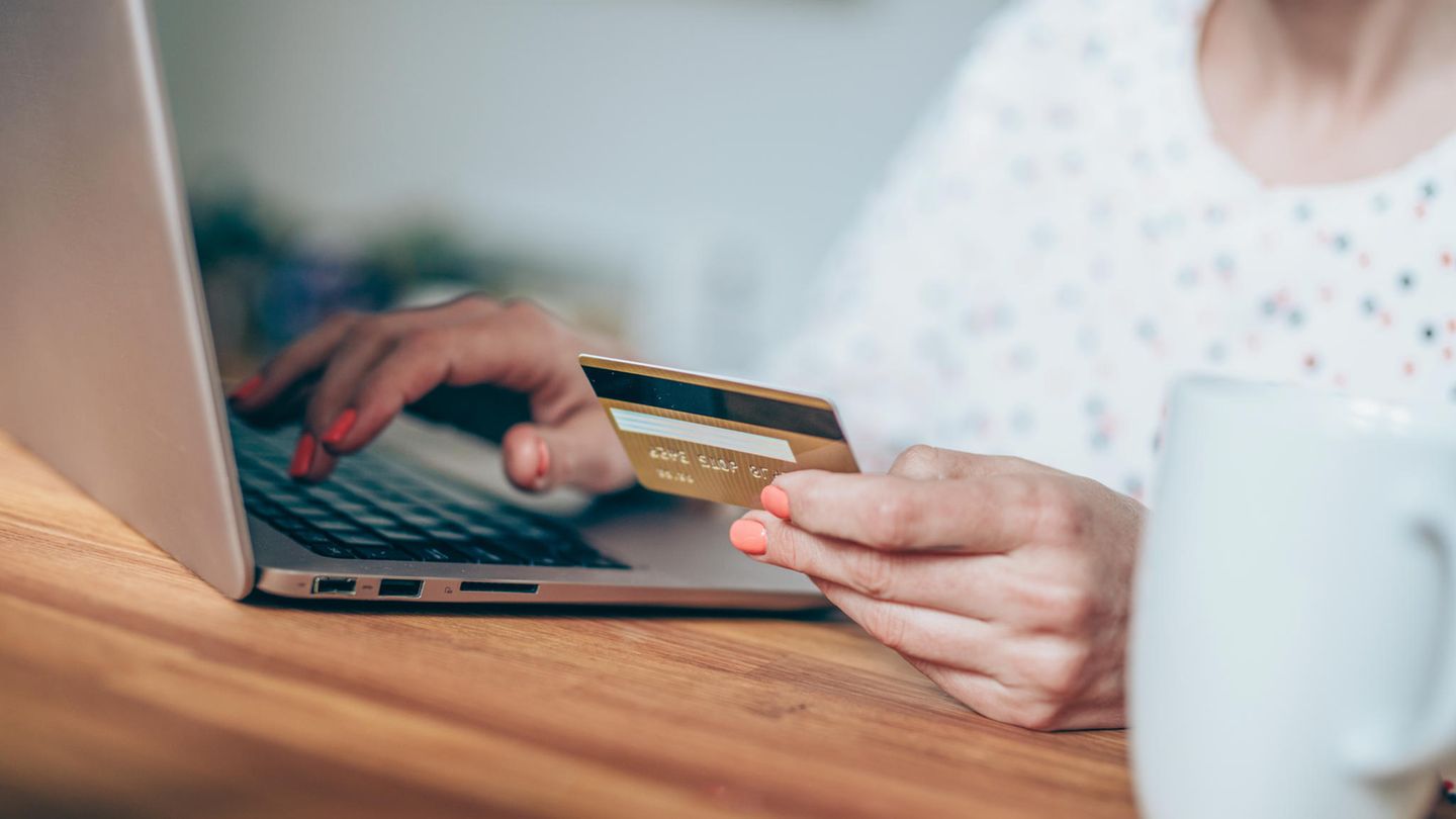 Symbolbild zum Thema Romance Scamming: Eine Frau sitzt mit Kreditkarte vor einem Rechner