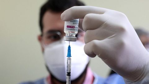 Arzt zieht Impfspritze mit Astrazeneca-Stoff auf