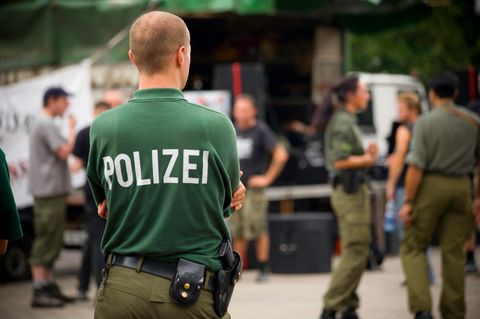 Ein Beamter mit Polizei-Shirt steht auf einem Hof