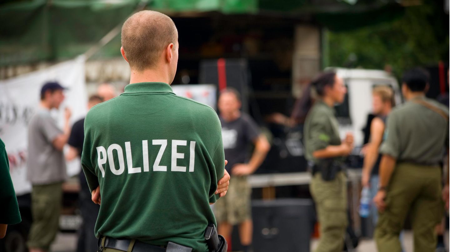 Ein Beamter mit Polizei-Shirt steht auf einem Hof
