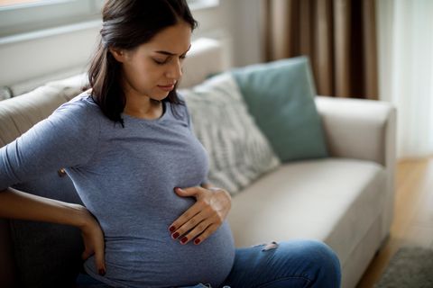 Schwangere Frau sitzt auf dem Sofa