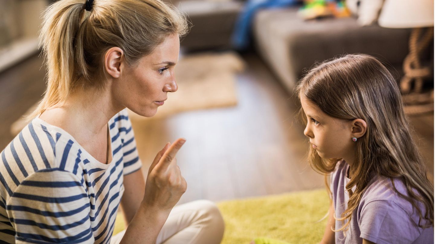 Mutter schimpft mit Tochter, während sie sich gegenüber auf dem Boden sitzen