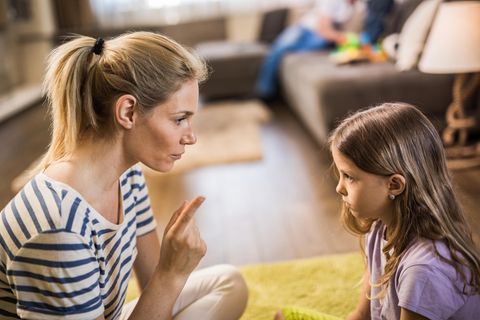 Mutter schimpft mit Tochter, während sie sich gegenüber auf dem Boden sitzen