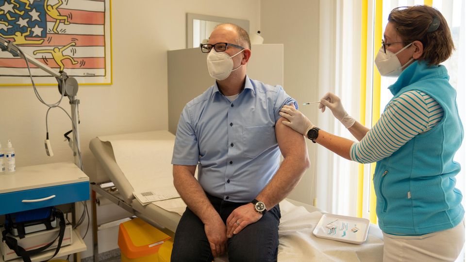 Ein Ärztin impft einen Patienten in ihrer Praxis gegen SARS-Cov-2.