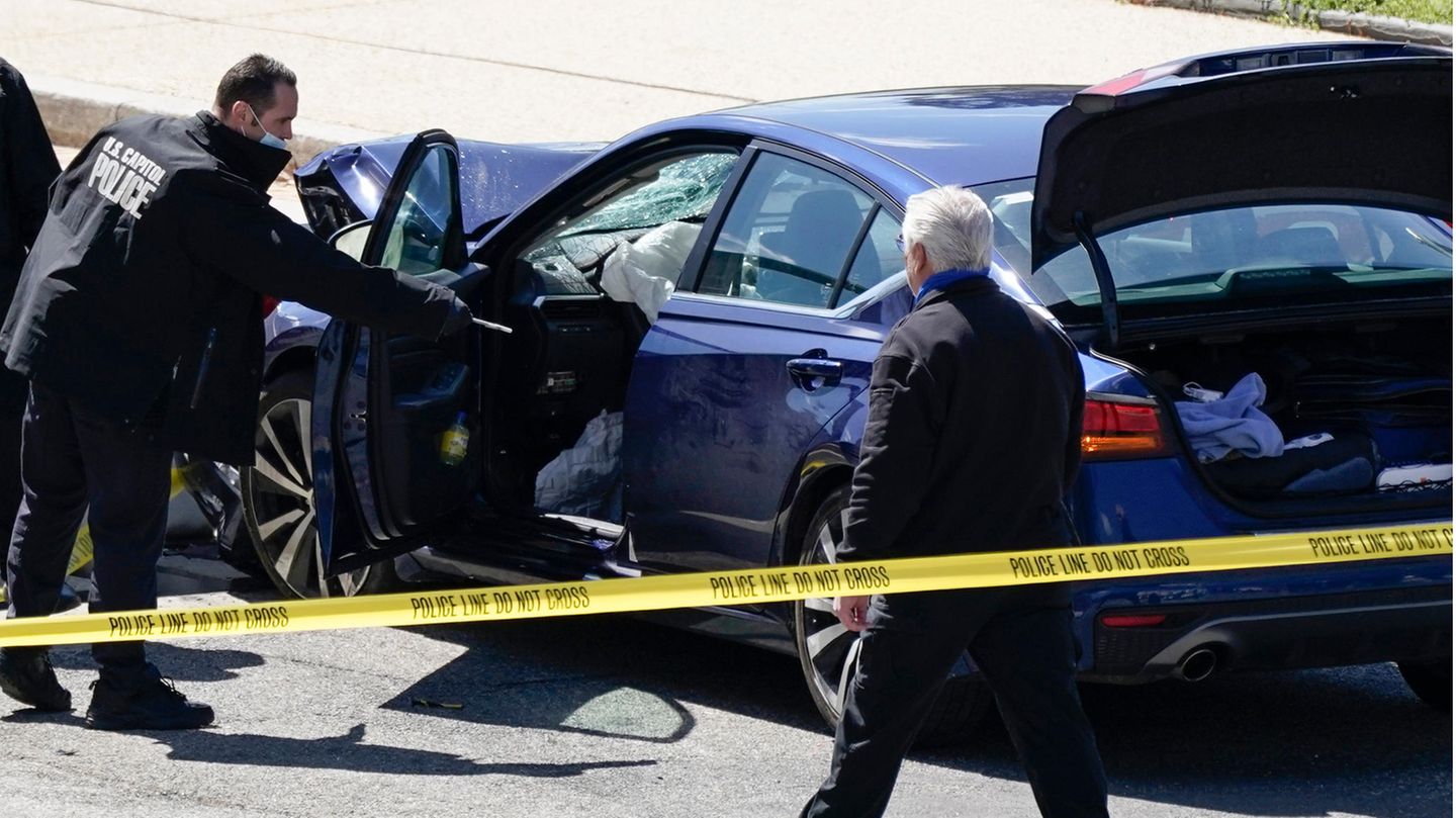 Ein Mann der "U.S. Capitol Police" steht an der geöffneten Fahrertür eines blauen BMW. Die Frontscheibe ist zersplittert
