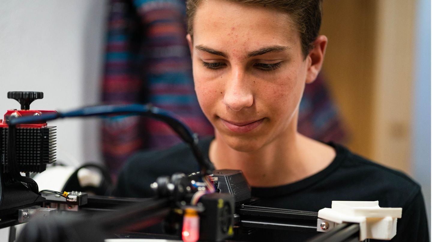 Ein Jugendlicher steht hinter einem 3D-Drucker