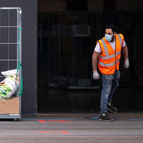 Ein Amazon-Mitarbeiter neben einem Haufen Paketen der Firma