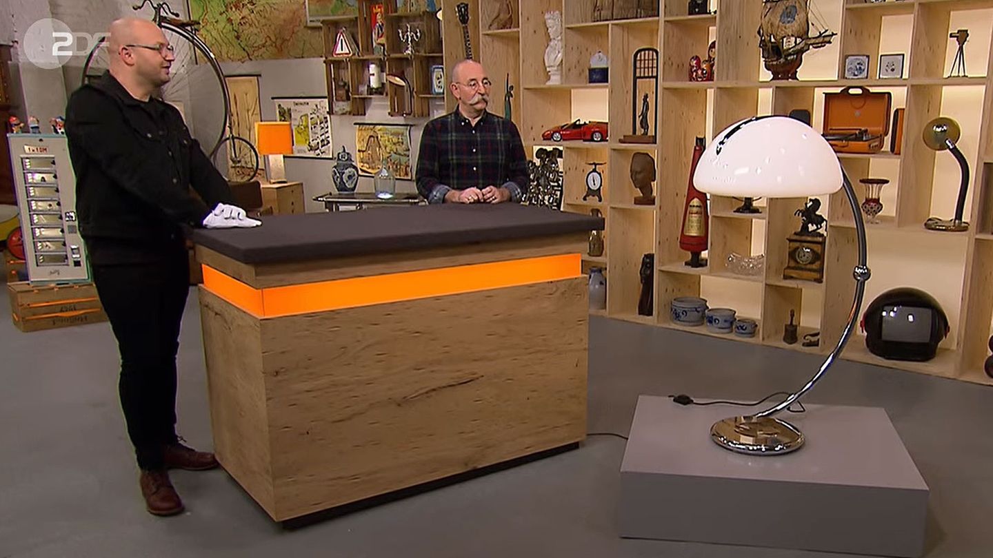 Sven Deutschmanek und Horst Lichter stehen im Studio von Bares für Rares neben einer riesigen Leuchte
