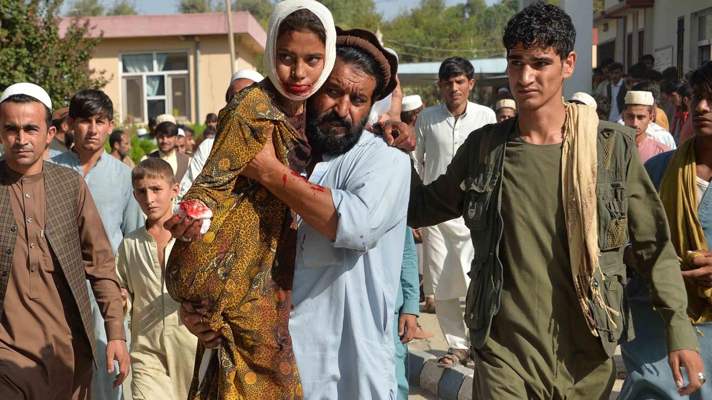 Nach einem Autobomben-Angriff der Taliban auf ein Regierungsgebäude im Oktober 2020 trägt ein Mann ein verletztes Mädchen zum Krankenhaus des Distrikts Ghani Khel nahe der afghanischen Stadt Jalalabad.