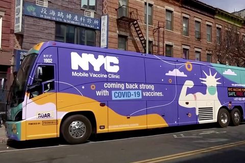 Ein gelb-lila-grüner Reisebus steht vor einem klassischen New Yorker Backstein-Gebäude mit Feuerleitern an der Fassade