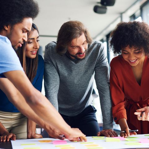Eine Gruppe multiethnischer Studierender beugt sich über ein Blatt