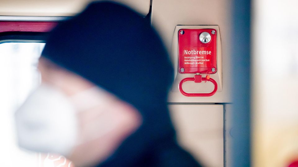Ein Fahrgast mit Mund-Nasen-Schutz steht in einer Berliner S-Bahn vor einer Notbremse
