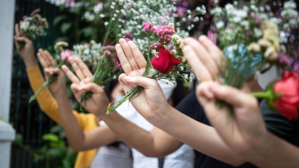 People make three-finger salutes while holding flowers in memory of the victims of the violent protests against the February 1 military takeover.People in Myanmar laid flowers in public places on Friday in memory of the victims of the violent protests ... Die Blumen als Erinnerung an die Opfer und drei Finger als Symbol der Opposition