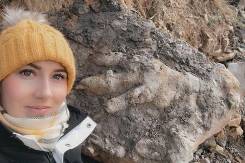 Die Archäologin Marie Woods mit dem Dinosaurier-Fußbadruck im Hintergrund