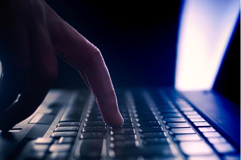 Mann schreibt auf einer Computertastatur