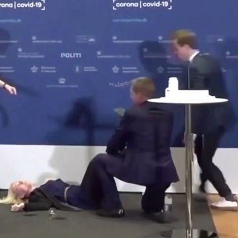 Mehrere Männer kümmern sich um die bei einer Coronavirus-Pressekonferenz in Dänemark zusammengebrochene Beamtin