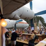 Eine Bar unterm Propeller im Juli 2019 beim Baum & Borke Open Air auf dem ehemaligen Flugplatz in Borkheide bei Potsdam: Diese Il-18 mit der Kennung "Tango Echo" wurde im Herbst 1989 hierher geflogen und ist Teil des Hans-Grade-Museums, das an den Flugzeugbauer erinnert.