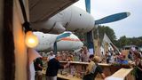 Eine Bar unterm Propeller im Juli 2019 beim Baum & Borke Open Air auf dem ehemaligen Flugplatz in Borkheide bei Potsdam: Diese Il-18 mit der Kennung "Tango Echo" wurde im Herbst 1989 hierher geflogen und ist Teil des Hans-Grade-Museums, das an den Flugzeugbauer erinnert.