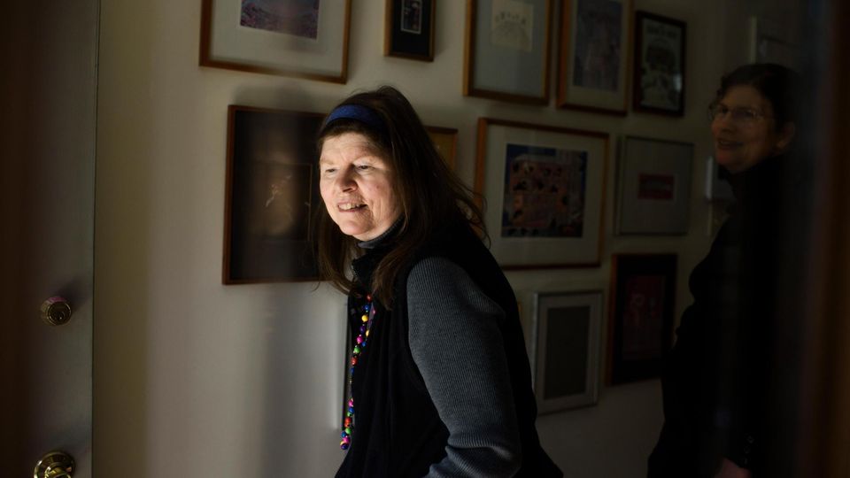 Lonni Sue vor einer Wand mit ihren Gemälden