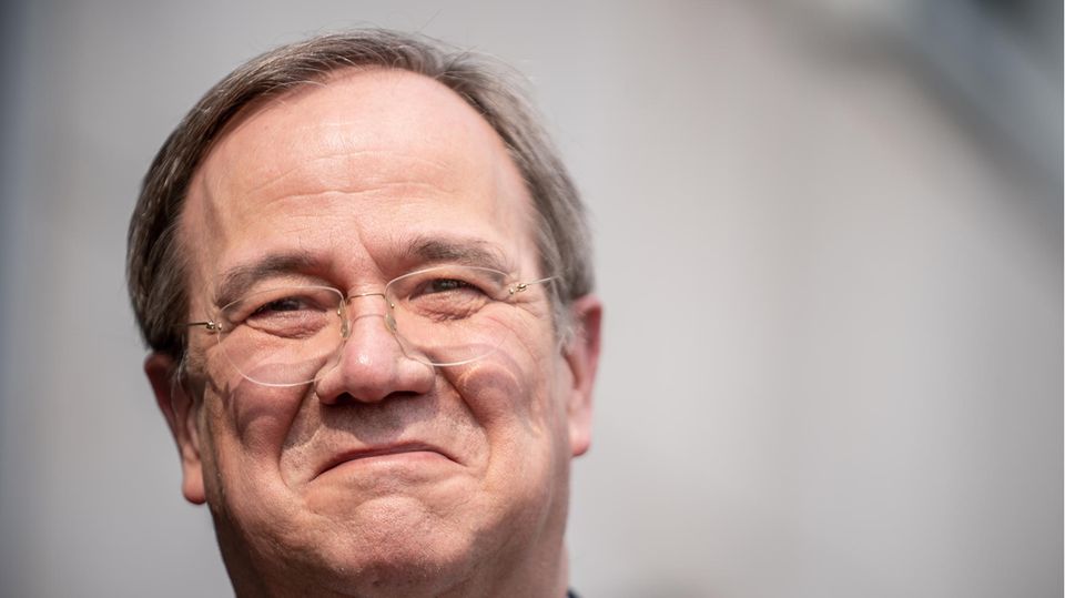Ein älterer weißer Mann mit randloser Brille und dunkelgrauem Seitenscheitel lächelt, während ihm die Sonne ins Gesicht scheint