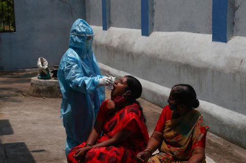 In der indischen Stadt Hyderabad nimmt ein Mitarbeiter des Gesundheitswesens einer Frau einen Mundabstrich ab