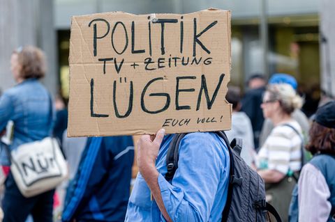 Ein Mann hält ein Plakat während einer Demonstration in Hamburg gegen die Corona-Maßnahmen