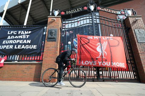 Zur Super League: Ein Mann fährt mit dem Fahrrad an einem Banner vor dem Anfield Stadion in Liverpool vorbei.