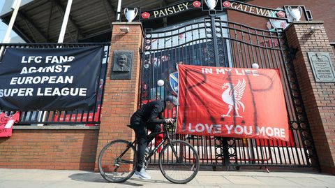 Zur Super League: Ein Mann fährt mit dem Fahrrad an einem Banner vor dem Anfield Stadion in Liverpool vorbei.