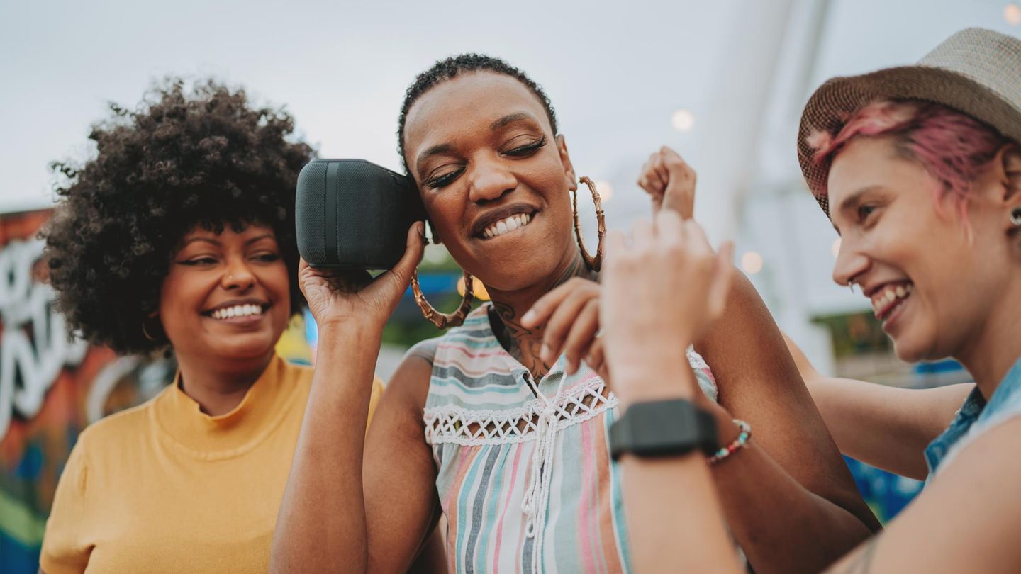 Outdoor-Lautsprechern: Junge Menschen hören Musik über den Lautsprecher