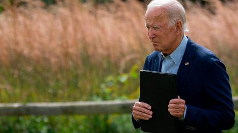 Joe Biden mit einer Kladde in der Hand vor einem Kornfeld