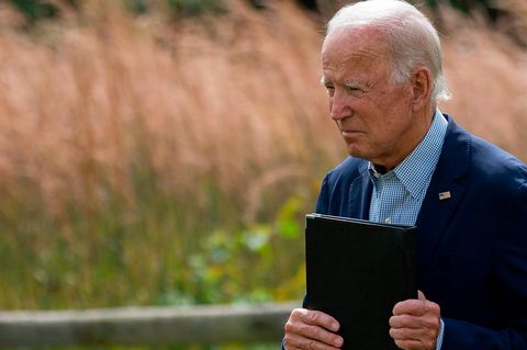 Joe Biden mit einer Kladde in der Hand vor einem Kornfeld