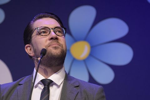 Der Parteivorsitzende der Schwedendemokraten, Jimmie Åkesson, vor dem Logo seiner Partei, einer blau-gelben Blume