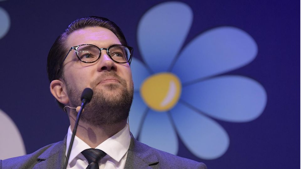 Der Parteivorsitzende der Schwedendemokraten, Jimmie Åkesson, vor dem Logo seiner Partei, einer blau-gelben Blume