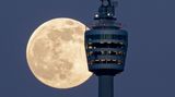 Der Vollmond schiebt sich hinter dem Stuttgarter Fernsehturm durch.