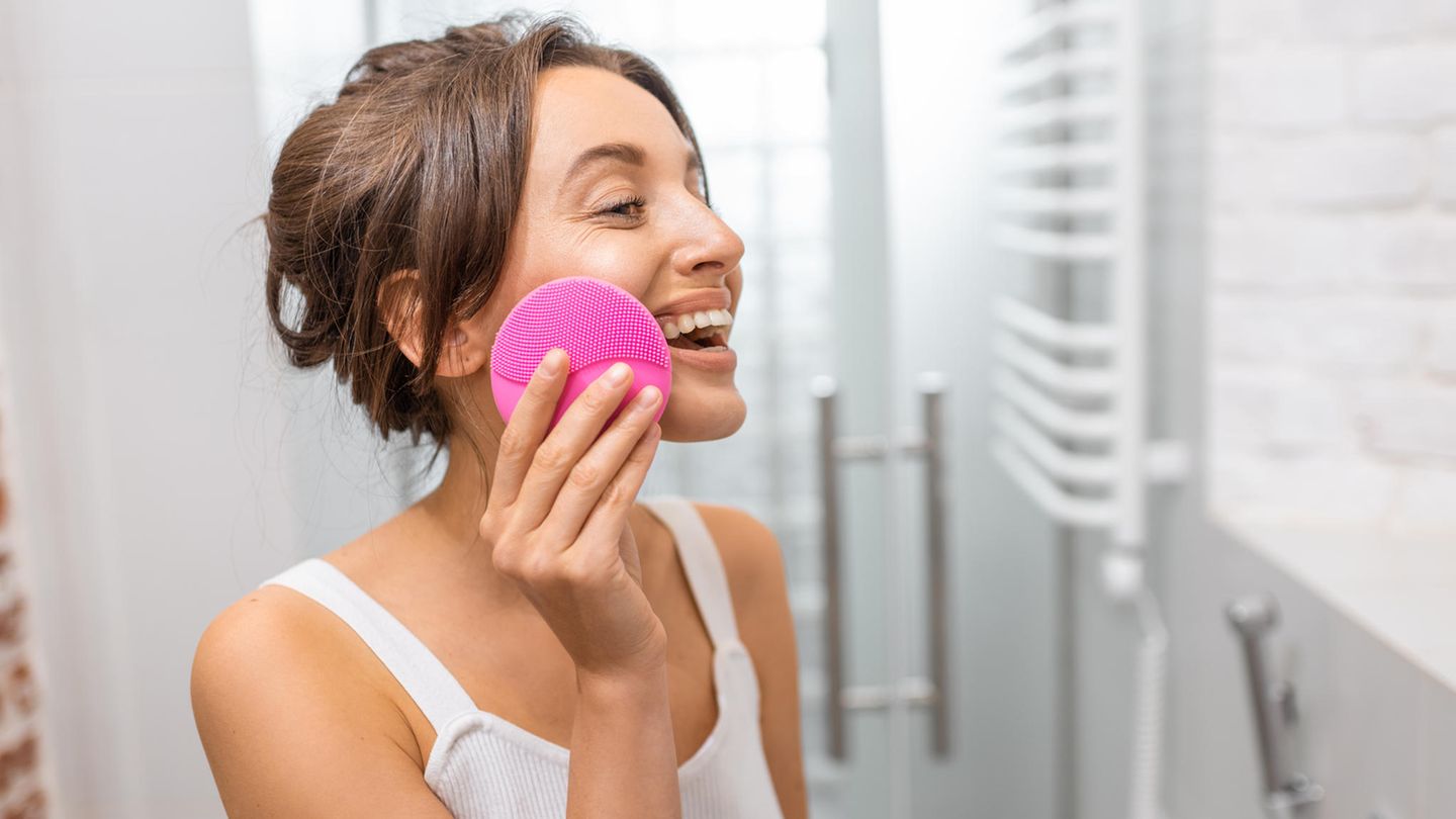 Frau nutzt elektrische Gesichtsbürste