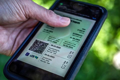 Ein israelischer Mann hält ein Smartphone in der Hand, auf dem der sogenannte "Grüne Pass" abgebildet ist