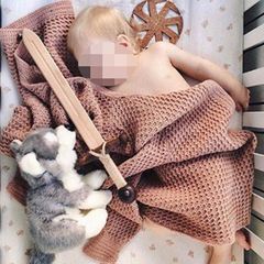 Blonder Säugling mit Plüsch-Wolf, Holzschwert und dem Neonazi-Symbol "Schwarze Sonne"