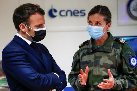 Eine weiße, dunkelblonde Frau in französischer Tarnfleck-Uniform erklärt einem weißen Mann im Anzug etwas